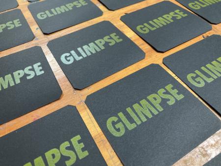 image: GLIMPSE, yellow on white on black card stock.